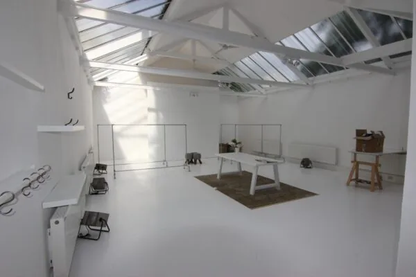 Lichte, minimalistische werkruimte met witte muren, glazen dak en moderne meubels aan de Graaf Florisstraat.